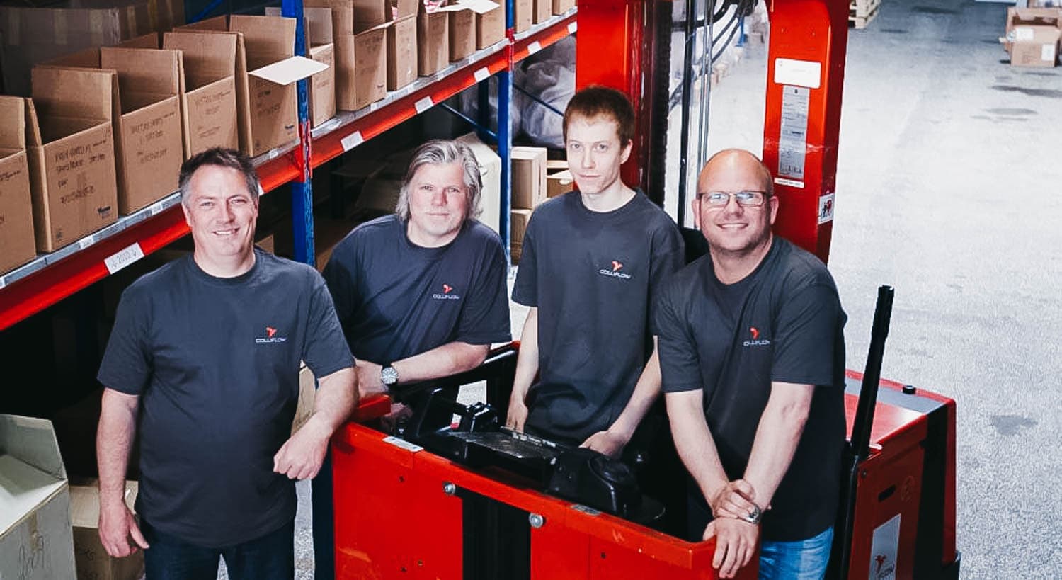 Four Colliflow employees stand in the warehouse and smile at the camera.